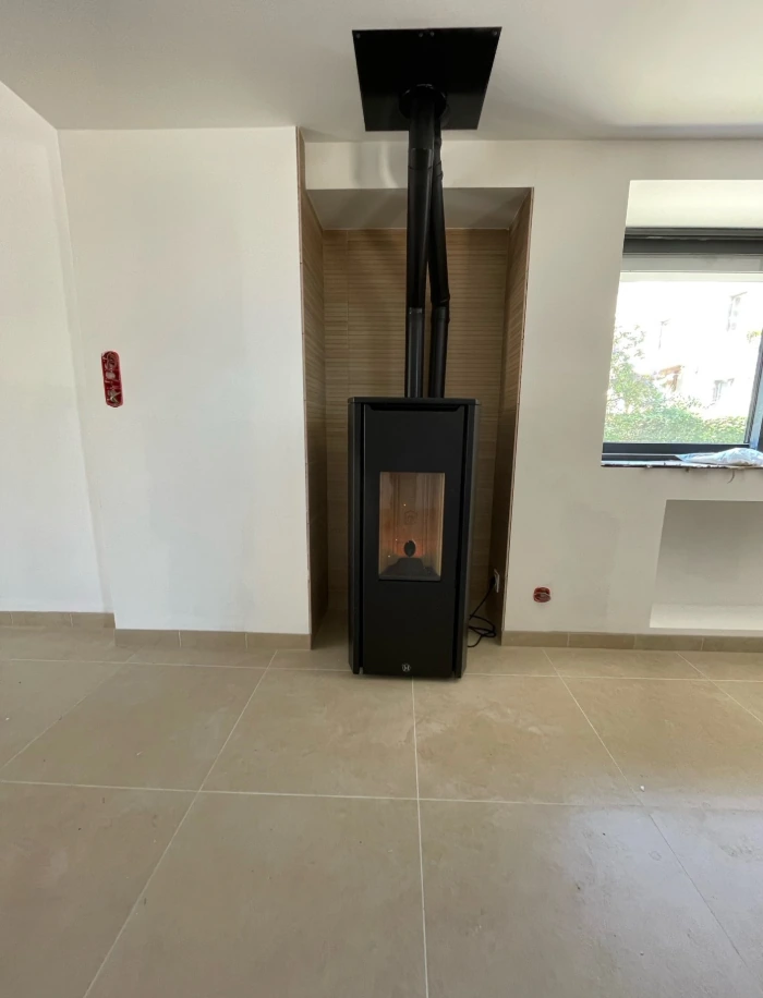 Poele a granules noir installe dans une niche avec conduit vers le plafond