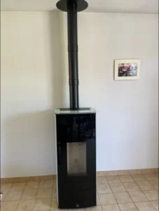 Poele a granules noir avec conduit vertical vers le plafond contre un mur blanc